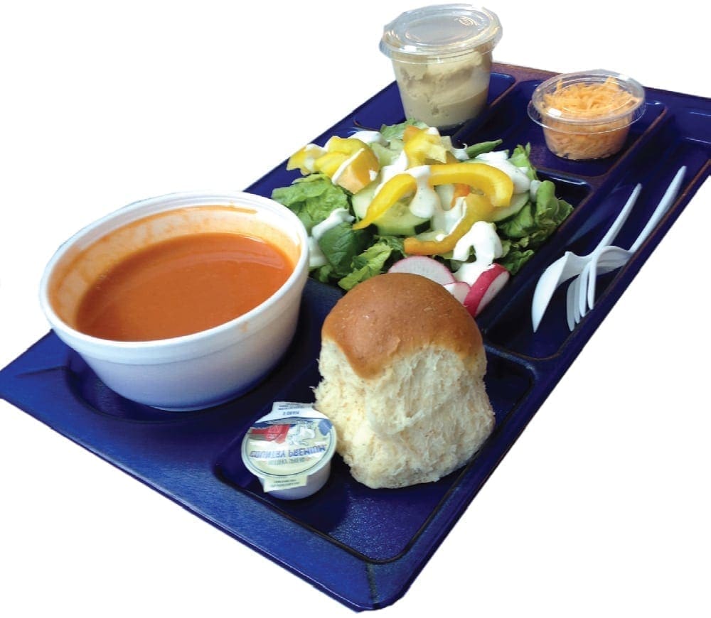 A school lunch tray with soup, salad, a roll, and condiments.