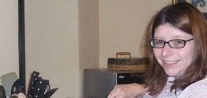 Andi wearing glasses and a light-colored shirt, smiling.