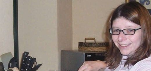 Andi wearing glasses and a light-colored shirt, smiling.