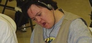 Angie wearing headphones and a vest, looking down.