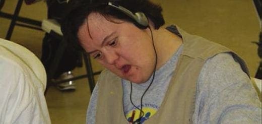 Angie wearing headphones and a vest, looking down.