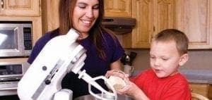 A woman and a boy in a kitchen with a stand mixer.