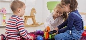 Three children playing with toys on the floor.