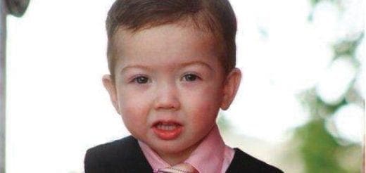 Young child in a formal shirt and dark vest looking toward the camera.