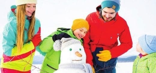 Family building a snowman in the snow.