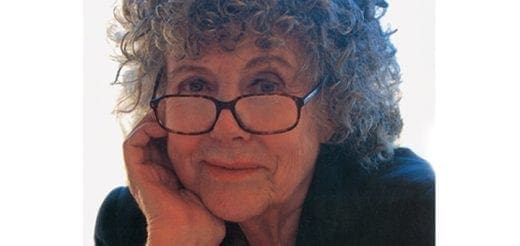 Eustacia Cutler wearing glasses and leaning her head on her hand.