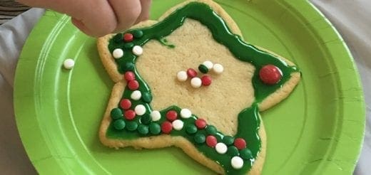 Star-shaped cookie decorated with green icing and colorful sprinkles on a green plate.