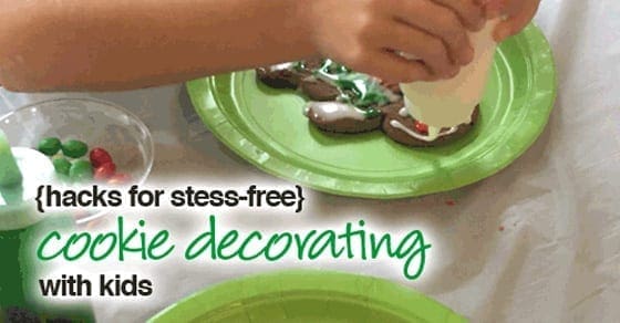 Hands decorating cookies with frosting and sprinkles.