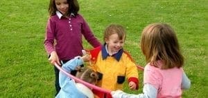 Children playing with a hula hoop in the grass