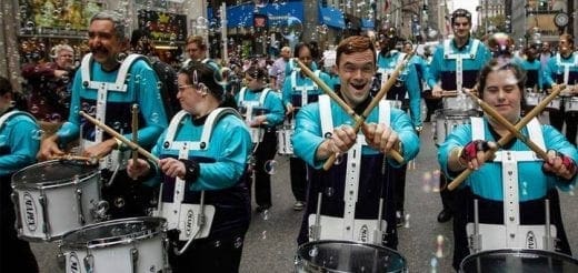 Drummers in matching turquoise and black uniforms playing in a parade.