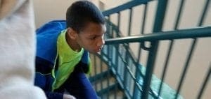 A young person in a blue and green jacket climbs stairs.