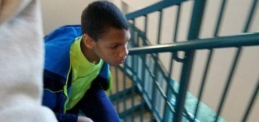 A young person in a blue and green jacket climbs stairs.