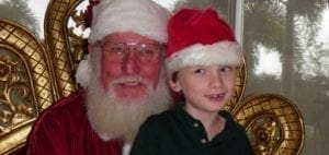 Santa Claus with a young boy in a Santa hat.