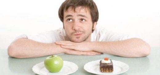 Man contemplating a choice between an apple and a piece of cake.