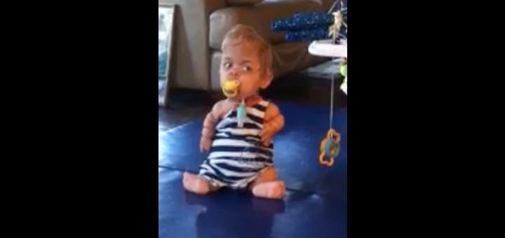 Samuel sitting on the floor with a pacifier.