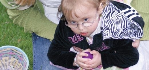 Emarie holding a purple egg and wearing glasses.