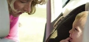 Woman leaning over to look at a baby in a car seat.