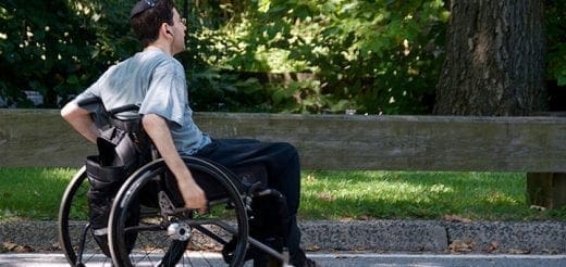 A person in a wheelchair moves alongside a park path.