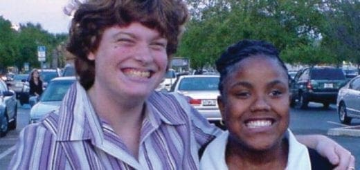 Two people smiling in a parking lot.