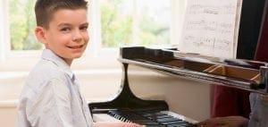 Boy smiling while playing the piano