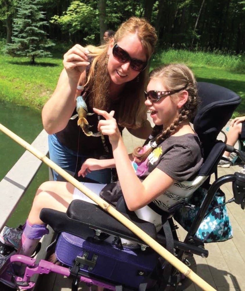 Shannon and Alyssa show off a small fish by the water.