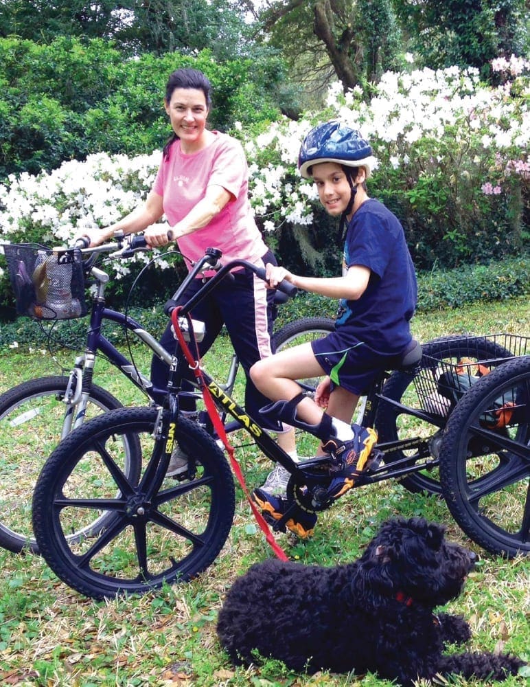 William and Korky on a tandem bicycle with a dog in front.