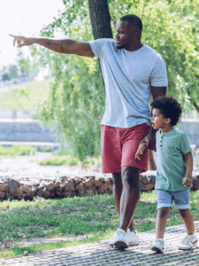 Man and child walking on a path in a park, man points ahead