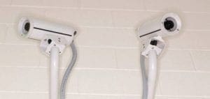 Two white security cameras mounted on poles
