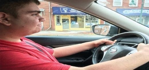 Matthew driving a car on a street.