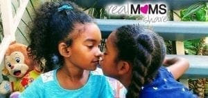 Two young girls, likely twins, share a tender moment.