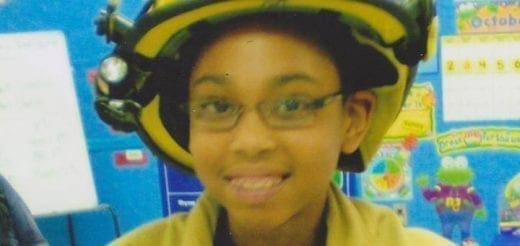 Young person wearing a firefighter helmet and jacket.