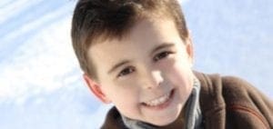Carter LaFramboise smiles in a brown jacket against a blurred sky background.