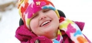 Cortney Kovack smiles while wearing a colorful hat and pink coat.