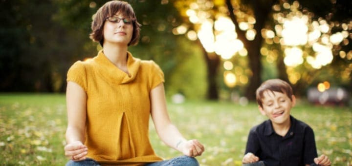 Woman meditating in a park with a boy in the background