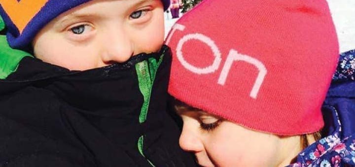 Two children wearing winter hats and jackets.