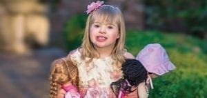 Amelia Grace Vitacco holds three dolls and wears a floral headband.