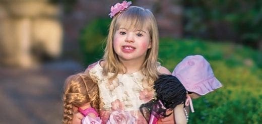 Amelia Grace Vitacco holds three dolls and wears a floral headband.