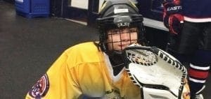 Jacob Weber in a yellow hockey uniform with a catcher's mitt.