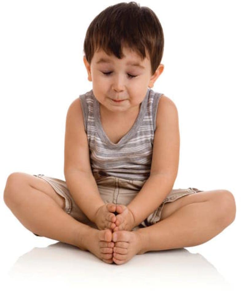 Child sitting cross-legged with hands clasped.