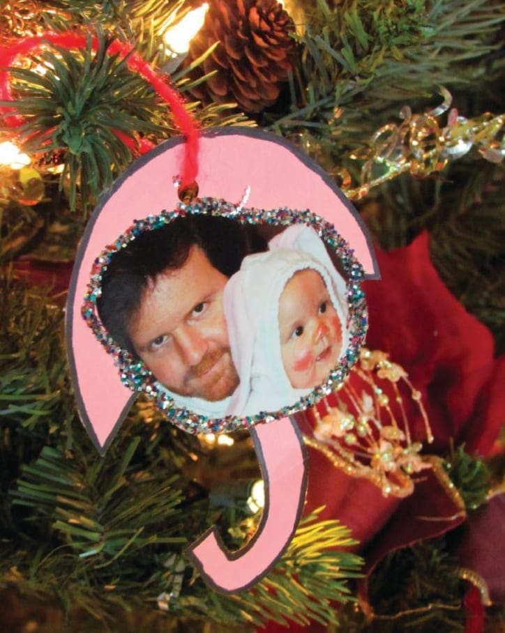Handmade umbrella-shaped Christmas ornament featuring a photograph of a person and a baby hanging on a tree.
