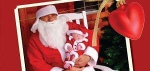 Santa holds a baby dressed in a Santa outfit.