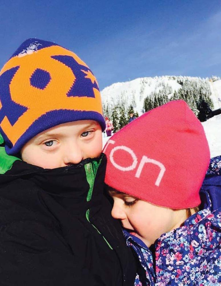 Lucas James Johnstone and Cameron Rose Johnstone in winter hats with snowy mountains behind them.