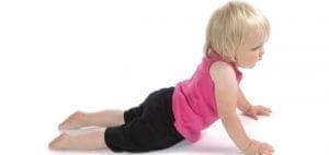 Toddler in a pink shirt and black shorts doing a yoga pose