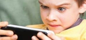 Young boy intensely playing a video game on a smartphone.
