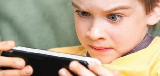 Young boy intensely playing a video game on a smartphone.