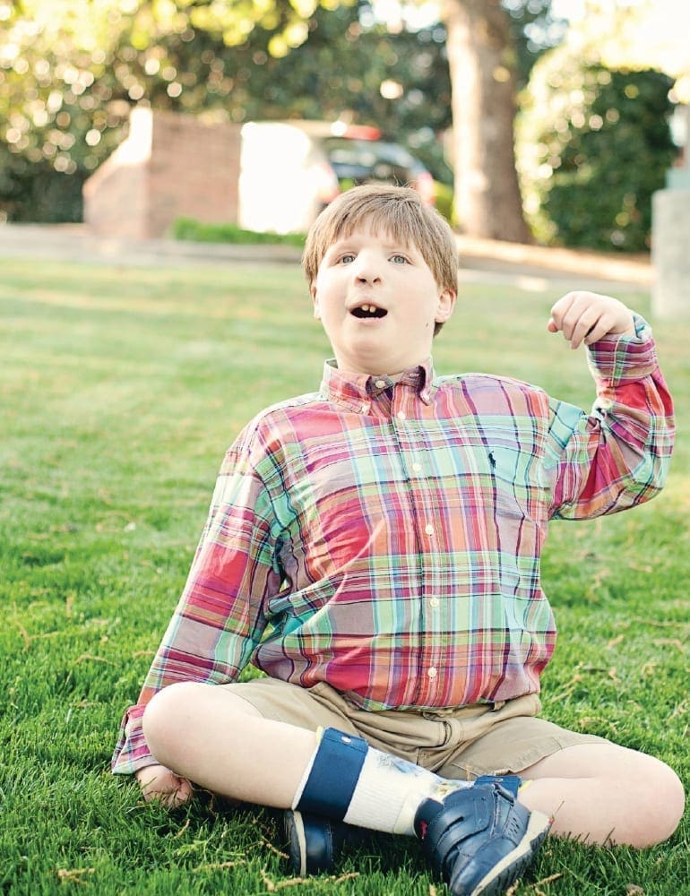 Jacob Elliott sitting on the grass flexing his arm.