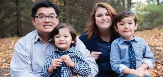 Family of four smiling outdoors in autumn.