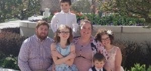 Family poses for a photo outdoors in front of a building.