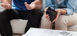 Couple with empty wallet and outstretched hands looking at bills.