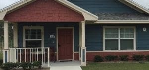 A blue house with a red door and a red gable.